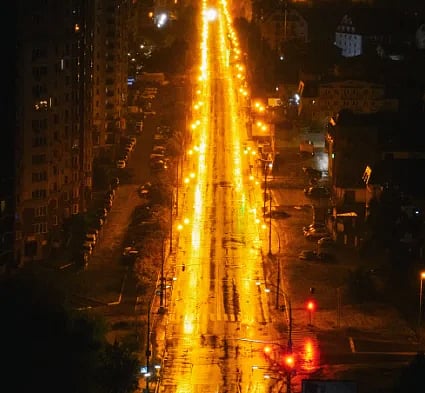 Vivid night scene of an urban street in Kyiv, showcasing glowing city lights and reflections.
