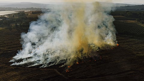 Aerial shot of smoke rising from a field in White River, Mpumalanga, depicting environmental impact.