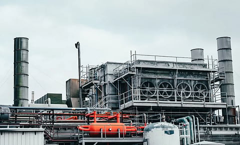 A modern industrial facility featuring complex machinery and infrastructure under a cloudy sky.
