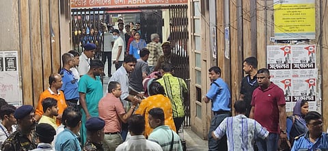 Crowd at hospital gate as people carry a person inside.