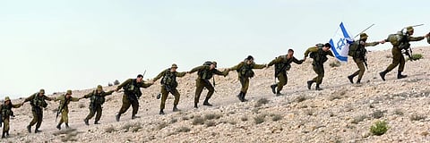 Israeli soldiers march in formation on a hill, showcasing discipline and unity in a military exercise.
