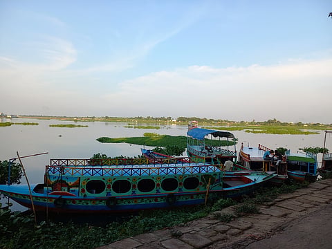 Colourful wooden boats moored on a calm Bangladeshi river.
