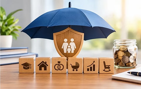 A blue umbrella shelters a wooden family shield above blocks symbolizing education, home, marriage, parenting, growth, and retirement, beside a jar of coins.