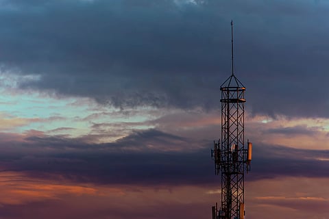A striking view of a radio tower silhouetted against a colorful and dramatic sunset sky.