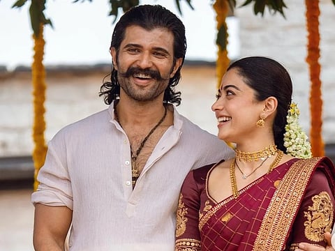Image of Vijay Deverakonda and rashmika Mandanna looking at him and smiling. the image is from the promotional tour of Ranabaali.