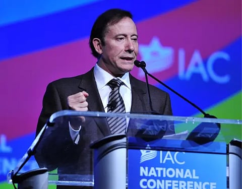  A man in a suit and tie stands at a podium, delivering a speech to an audience.