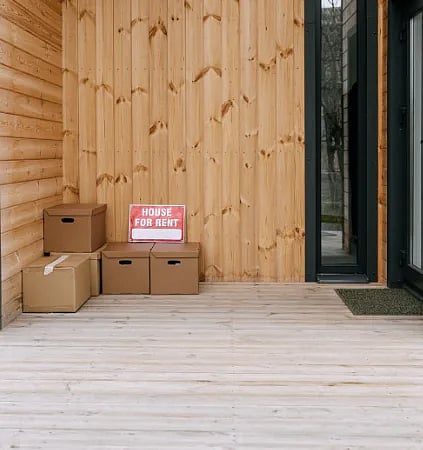 A wooden porch with boxes and 'House for Rent' sign, perfect for real estate listings.
