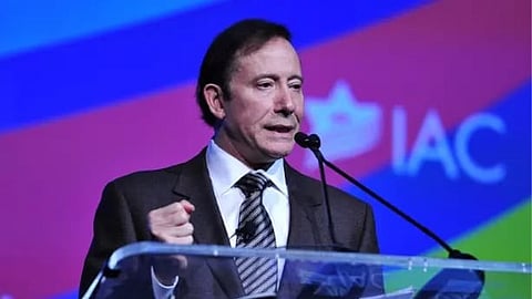  A man in a suit and tie stands at a podium, delivering a speech to an audience.