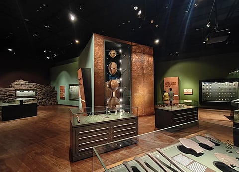 Image of Bihar Musuem from inside in a dimly lit room where many artifacts are placed inside a glass cage and some are placed on walls