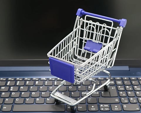A mini shopping cart placed on a laptop keyboard, symbolizing online shopping and digital retail.
