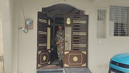 इस तस्वीर में एक सैनिक एक घर के दरवाज़े पर खड़ा है।