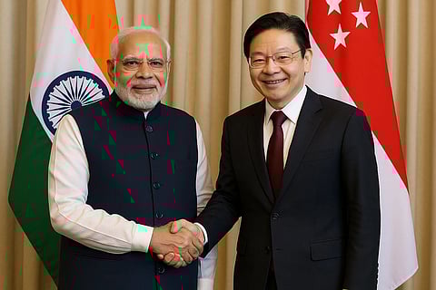 सिंगापुर के प्रधानमंत्री लॉरेंस वोंग, प्रधानमंत्री नरेंद्र मोदी अपने देश के तिरंगो के सामने हाथ मिलाते हुए 