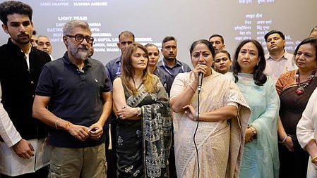 बहुत सारे लोग खड़े है और एक महिला माइक ले कर खड़ी है 