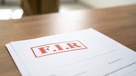 इस तस्वीर में एक मेज़ है, जिस पर "FIR" लिखा हुआ एक कागज़ रखा है।