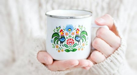 एक सफ़ेद रंग का कप एक हाथ के ऊपर है 