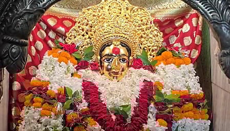 देवी माँ की मूर्ति है जिस पर फूलो की माला चढ़ी है 