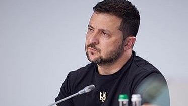 यूक्रेनी राष्ट्रपति वोलोदिमीर जेलेंस्की बैठे है और उन्होंने ने ब्लैक टीशर्ट पहना है 