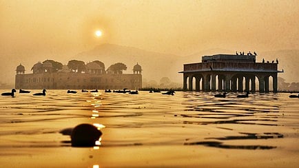 गंगा नदी की तस्वीर जिस में सूर्य उदय होते दिख रहा है 