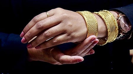 सोने के कंगन पहने एक महिला का हाथ 