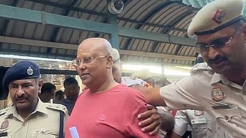 दो पुलिस स्वामी चैतन्यानंद महाराज को पकड़ कर ले जा रहे है। 