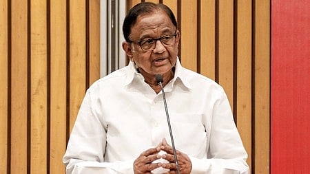 कांग्रेस के वरिष्ठ नेता चिदंबरम कुर्सी पर बैठे है और उन्होंने वाइट शर्ट पहना है।  