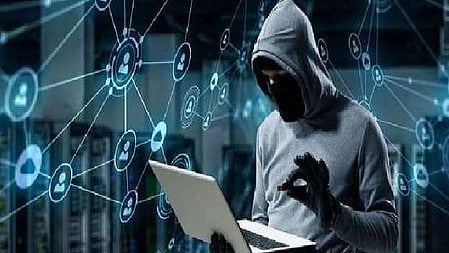 एक इंसान खड़ा है और उसके हाथ में लैपटॉप है और वो हूडी पहना है 