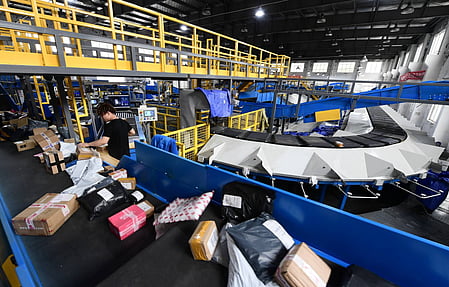 Automated warehouse logistics system sorting parcels with conveyor belts and workers – modern e-commerce supply chain and courier distribution center.