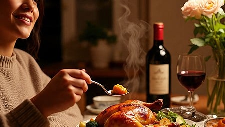 एक लड़की बैठी है और सामने टेबल पर ग्लास, खाना और फूल रखे है 