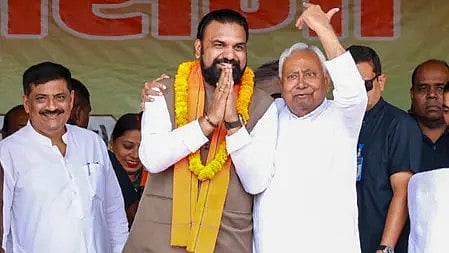 स्टेज पर मुख्यमंत्री नीतीश कुमार एक अन्य व्यक्ति के साथ मुस्कुराते हुए खड़े हैं, बिहार चुनाव 2025 के कार्यक्रम के दौरान।