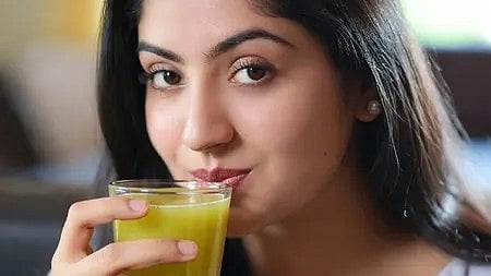 एक लड़की हेल्दी जूस पीती हुई, स्वास्थ्य और पोषण का आनंद लेती हुई।