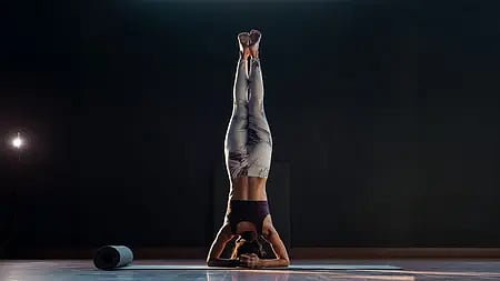 "हैंडस्टैंड करती हुई लड़की, योग अभ्यास में संतुलन और ताकत दिखाते हुए|