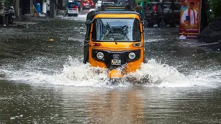 भारी बारिश में जलभराव के बीच चलती ऑटो रिक्शा का दृश्य|