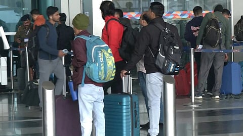 दिल्ली एयरपोर्ट पर चेक-इन काउंटर के पास खड़े हुए यात्री, हाथो में ट्रॉली बैग लिए हुए। 