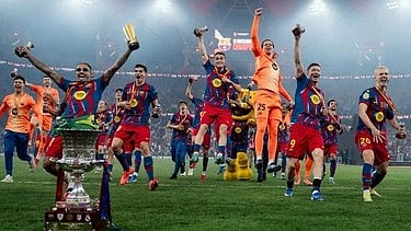 फुटबॉल टीम जीत का जश्न मनाती हुई,ट्रॉफी को ऊपर उठाए हुए। 