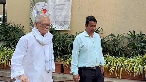 मतदान केंद्र के बाहर गीतकार गुलज़ार एक व्यक्ति के साथ चलते हुए।