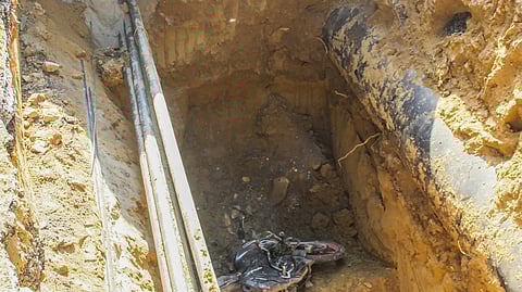 खुदाई किया हुआ गहरा गड्ढा दिखाई दे रहा है, जिसमें मिट्टी की दीवारें और किनारे पर पाइप लाइन पड़ी है।