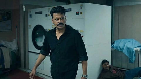 एक कमरे में मनोज बाजपेयी और एक दूसरे आदमी को देखा जा सकता है, संभवत एक लांड्री का दृश्य है। 