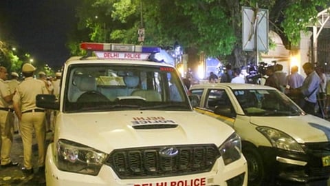 रोड पर पुलिस की गाड़ी, पुलिस और कुछ आम आदमी को देखा जा सकता है। 