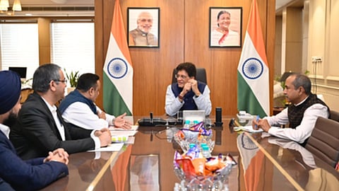 केंद्रीय वाणिज्य मंत्री पीयूष गोयल कार्यालय में अधिकारियों और व्यापार प्रतिनिधियों के साथ बैठक करते हुए, पीछे भारतीय झंडे और प्रधानमंत्री नरेंद्र मोदी की तस्वीर लगी हुई है।