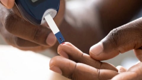 एक व्यक्ति ग्लूकोमीटर की स्ट्रिप पर उंगली से खून की बूंद लगाकर ब्लड शुगर की जांच करते हुए।