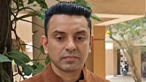 भूरा कपड़ा पहने तहसीन पूनावाला गंभीर मुद्रा में दिख रहे हैं 