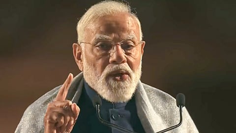 माइक के सामने खड़े होकर भाषण देते पीएम मोदी और ऊँगली से इशारा कर रहे हैं। 
