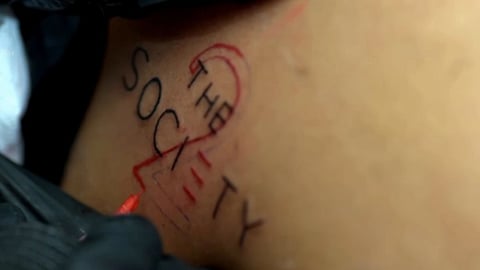 इस दृश्य में द सोसाइटी का टैटू दिख रहा है 