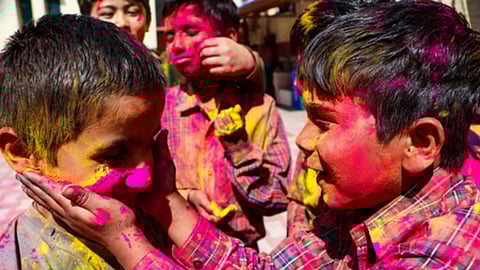 होली के मौके पर बच्चे एक-दूसरे को गुलाल लगाकर रंगों के साथ खुशी मनाते हुए।