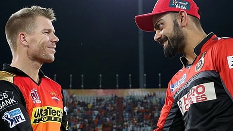 विराट कोहली और डेविड वॉर्नर आईपीएल मैच के दौरान मैदान पर एक-दूसरे से बातचीत करते हुए, दोनों अपनी-अपनी टीम की जर्सी में।
