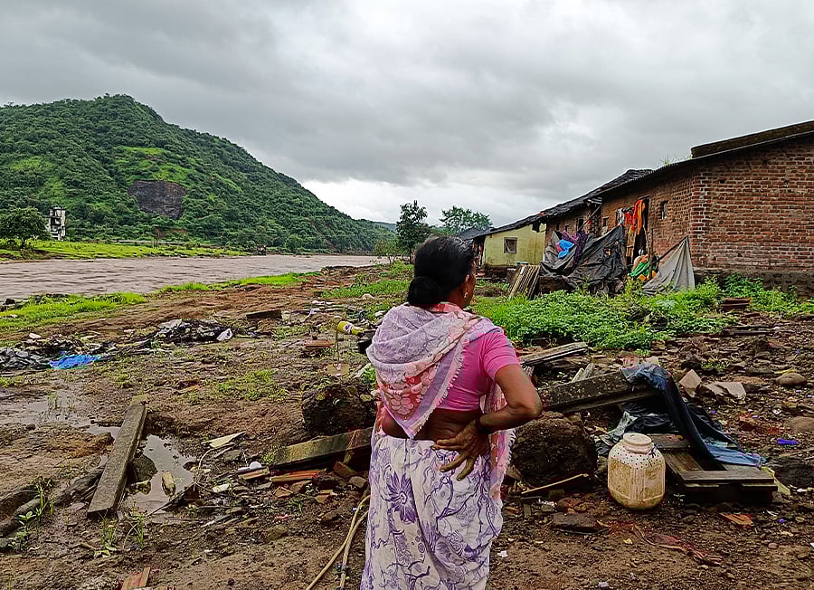 तबाही के बाद अपने घर को देखती महिला