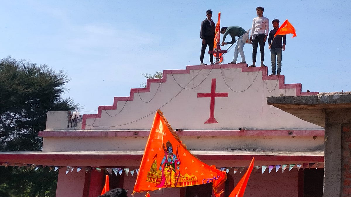 A picture of the right-wing activist putting a saffron flag on a cross.