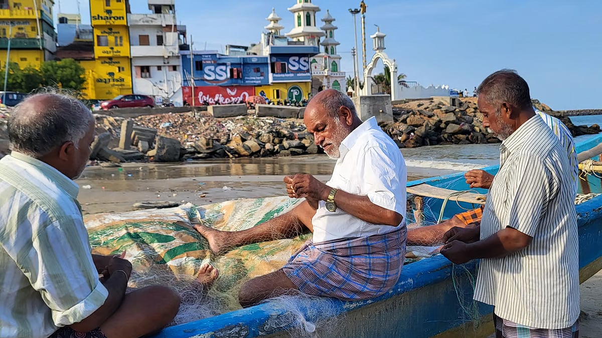 Mariasusai (middle) inspects fishing nets with his coworkers at the Vavathurai coast in Kanniyakumari.