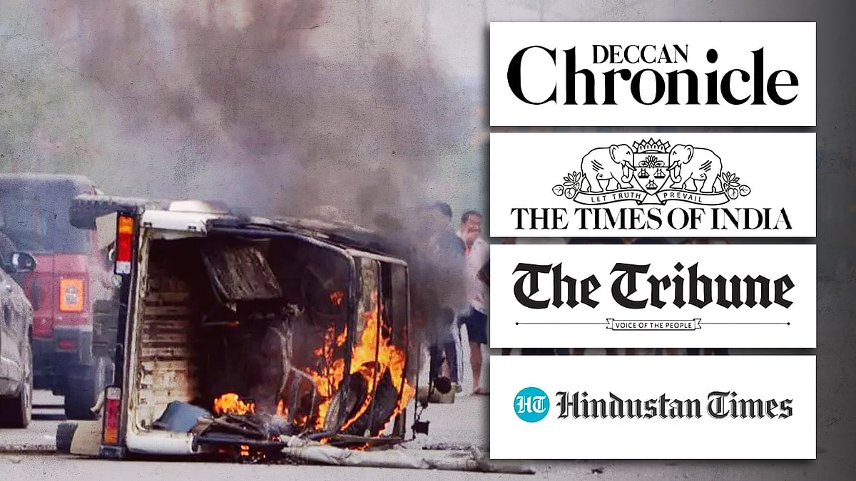 An overturned car engulfed in flames in the middle of a street in Manipur.