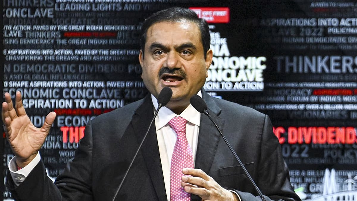 Gautam Adani, with headlines from newspapers behind him.